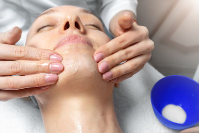 Cropped hands of beautician massaging woman at spa