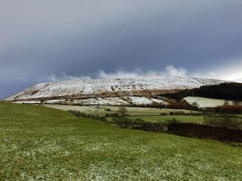 Scenic view of grassy field against cloudy sky