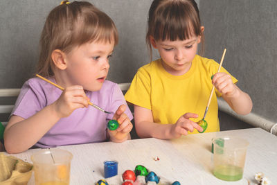 Children coloring easter eggs with paints. preparing for a happy easter holiday