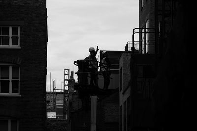 Man working on building against sky