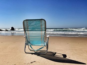 Deck chairs on beach against clear sky