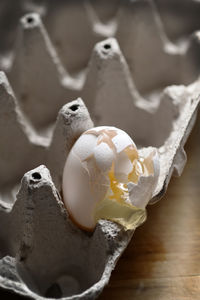 Close-up of broken egg on crate at table