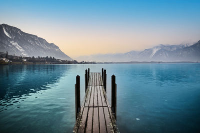 Wooden posts in lake against sky