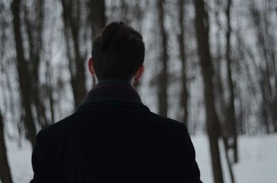 Rear view of man in forest during winter