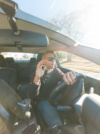 Side view of man driving car