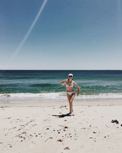 Full length of young woman in bikini walking at beach