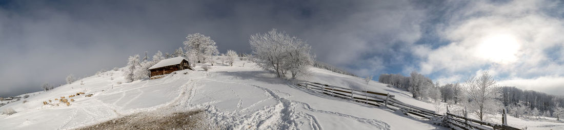 Panoramic view of snow covered landscape against sky