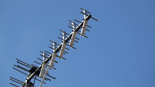 Low angle view of telephone pole against clear blue sky