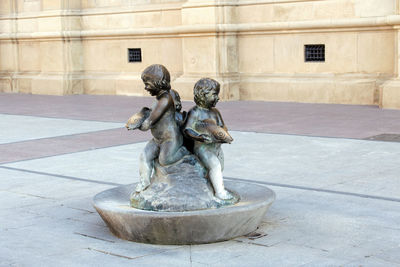Statue on fountain against building in city
