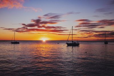 Silhouette sailboat in sea against sky during sunset