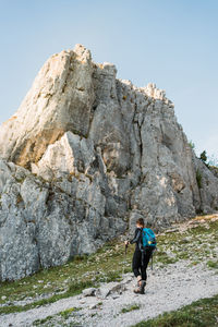 Low angle view of woman hiking in a rocky environment with backpack and hiking poles.