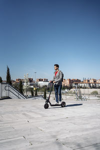 Man riding electric scooter on footpath