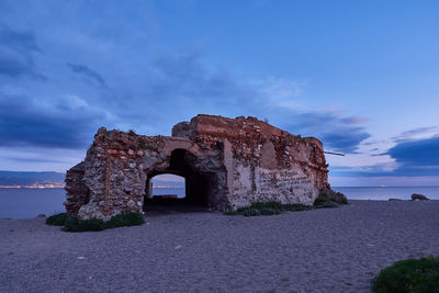 Stone wall by sea against sky