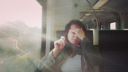 Woman holding eyeglasses while traveling in train