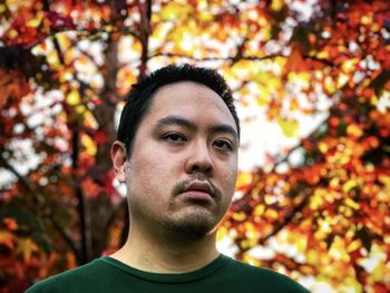 Portrait of young man with autumn leaves at sunset.