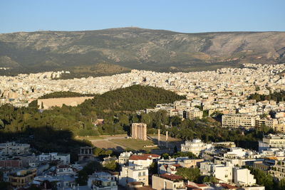 Temple of olympian zeus by townscape and mountains against sky