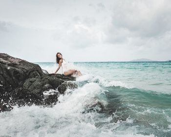 Young woman in sea against sky