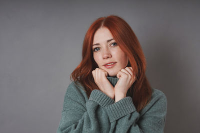 Portrait of young woman standing against wall