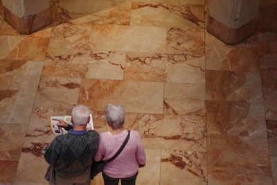 High angle view of senior couple with book standing in museum