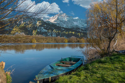 A rowing boat is moored on the shore of a small lake in fine weather