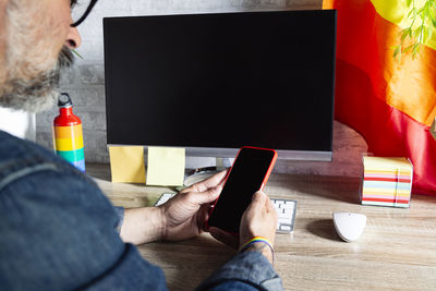 Man in the office with cell phone and lgbt accessories and gay flag. lgbtqia culture.