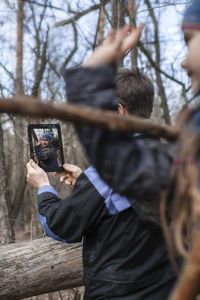 Boy holding digital tablet while standing outdoors