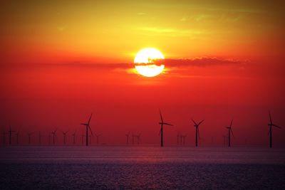 Silhouette of wind turbine against sky during sunrise 