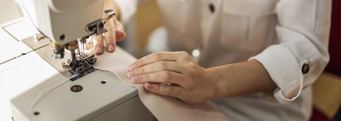 Midsection of woman using sewing machine