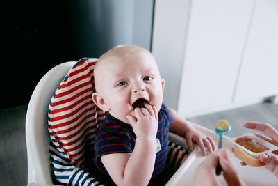 Cropped image of parent feeding food to cute baby boy