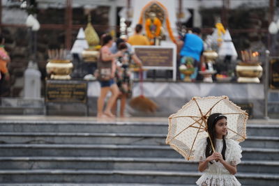Girl with umbrella standing against temple