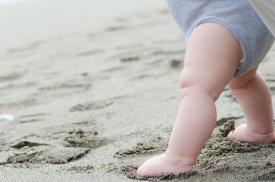 Low section of toddler standing at beach