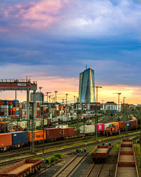 Railroad tracks in city against sky during sunset