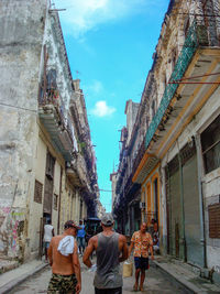 Rear view of people walking on street amidst buildings in city