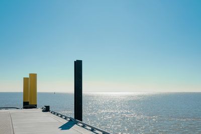 Scenic view of sea against clear blue sky with the edge of a pier