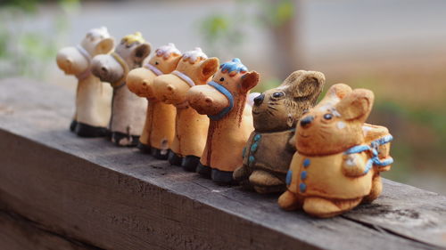 Close-up of animal figurines arranged on wooden railing