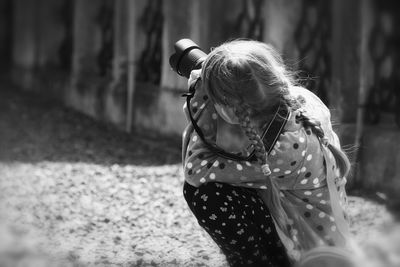 Close-up of girl photographing while crouching outdoors