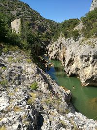 River amidst rocky mountains on sunny day