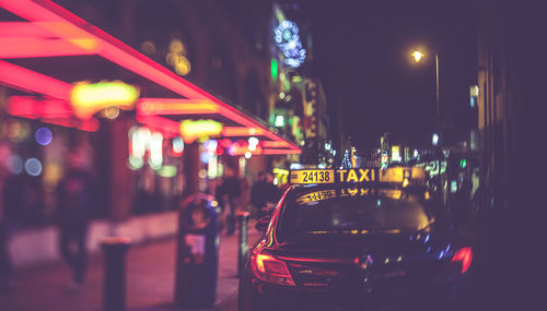 Cars on illuminated street in city at night