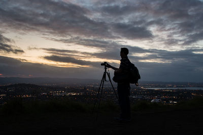 Silhouette man photographing against sky during dusk