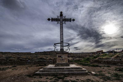 Low angle view of cross on field against sky