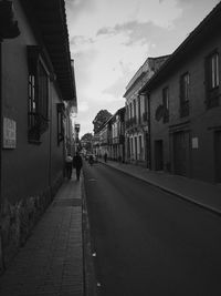 Man walking on road along buildings