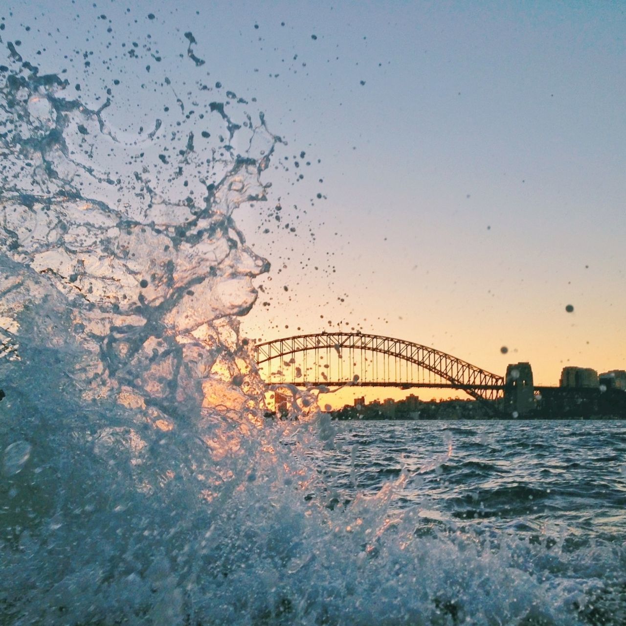 water, connection, built structure, architecture, bridge - man made structure, bird, sky, river, sunset, sea, waterfront, nature, bridge, building exterior, animal themes, animals in the wild, wildlife, flying, outdoors, clear sky