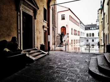 Rear view of man walking on street amidst buildings