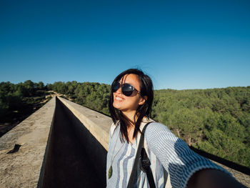 Portrait of young woman wearing sunglasses standing on land