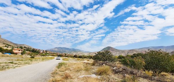 Road leading towards mountains against sky