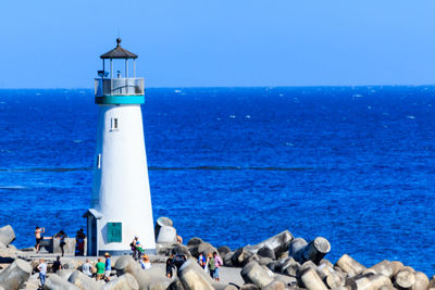 People swimming in sea against clear blue sky