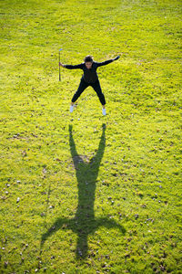 Aerial view on a golfer with success holding golf club  and jumping on the fairway with shadow.