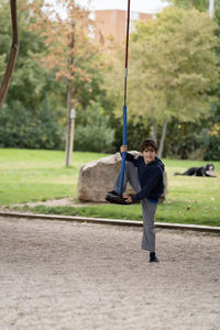 Happy kid smiling getting on disc swing in a urban park in madrid.