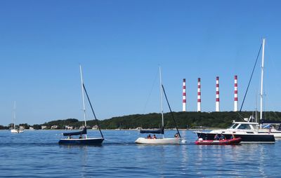 Sailboats moored in harbor against clear blue sky