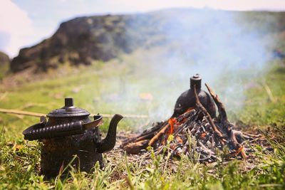 Close-up of old rusty kettle on land by campfire